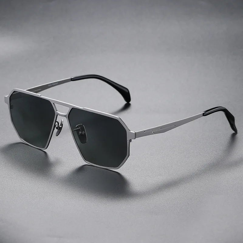 Aero Edge Aviator Sunglasses in titanium with a sleek silver finish and dark octagonal lenses, viewed at an angle on a grey background.
