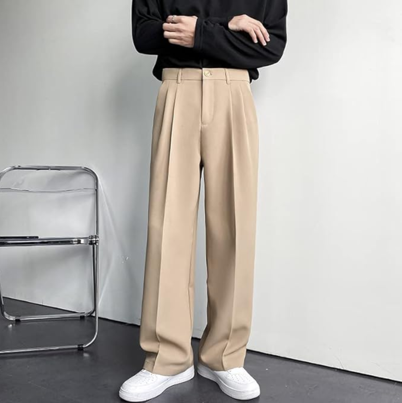 Men's Arno Trousers in beige linen, tailored fit, front view. Model wearing pleated chinos with a black shirt and white sneakers.