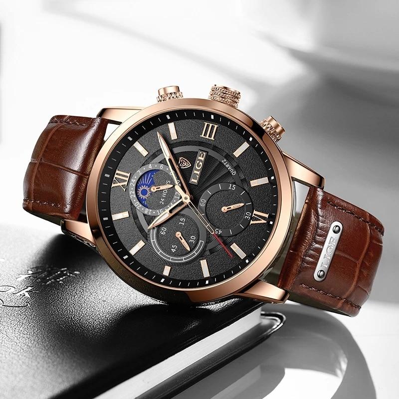 Angled view of Aurelius Timepiece men's watch with gold case, black dial, and brown leather strap, resting on a dark surface.