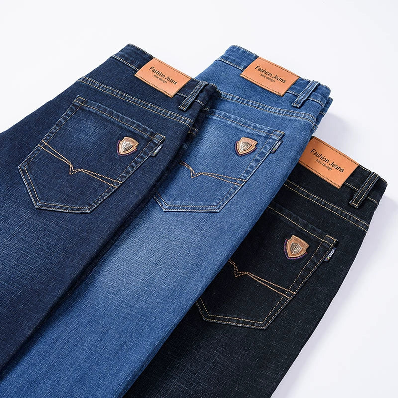 Three pairs of men's premium cotton classic fit trousers in dark blue, light blue, and black, displayed to show the back pocket detail with stitching and a leather-like patch.