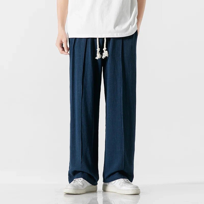 Elysium Drift blue linen sweatpants with a relaxed fit, shown on a male model from a front view, paired with a white t-shirt and white sneakers.