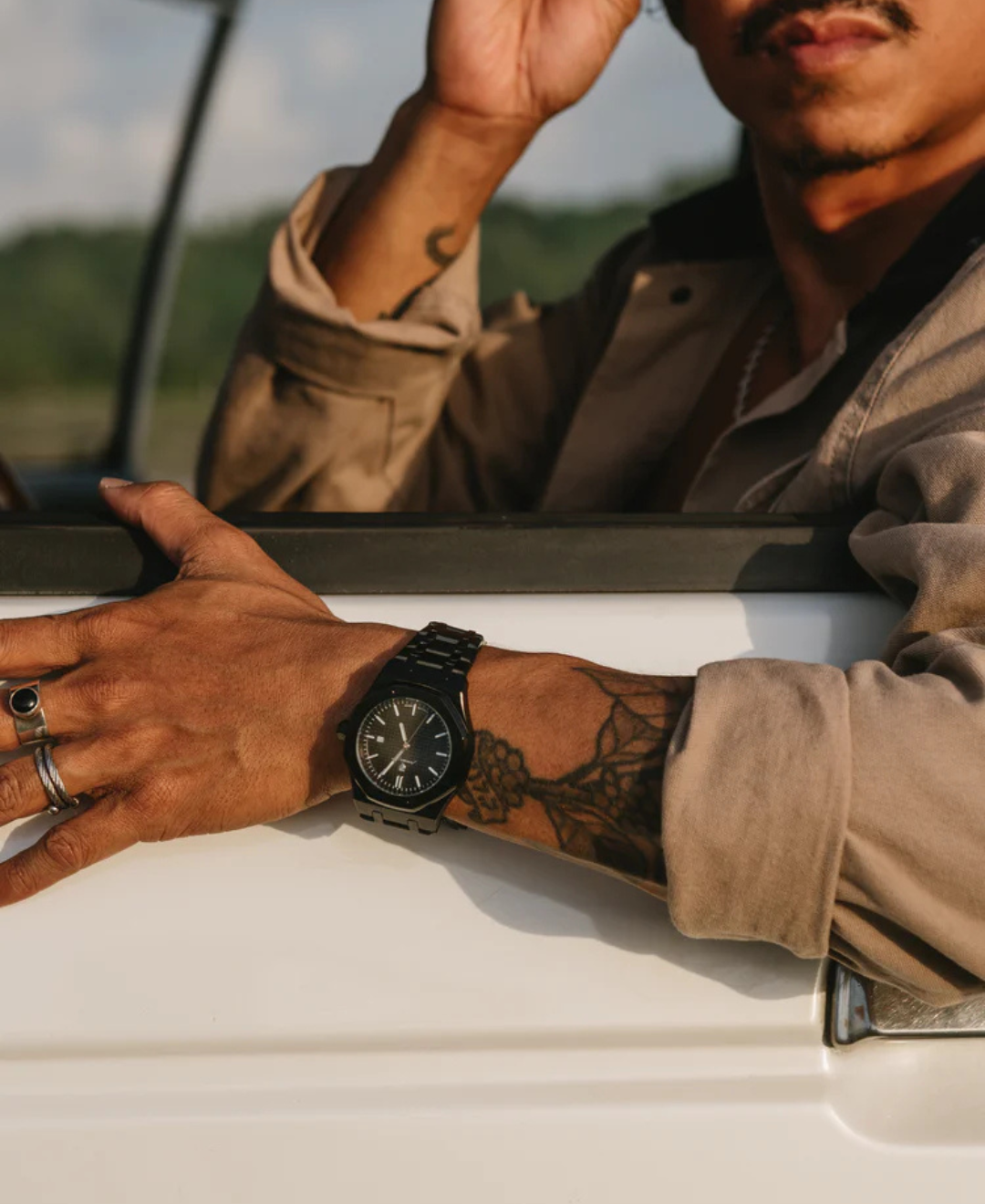 Kings Oak Oak Wood Furniture Handcrafted Finish: Man's arm with a black watch and tattoos resting on a car door, with part of his face visible.