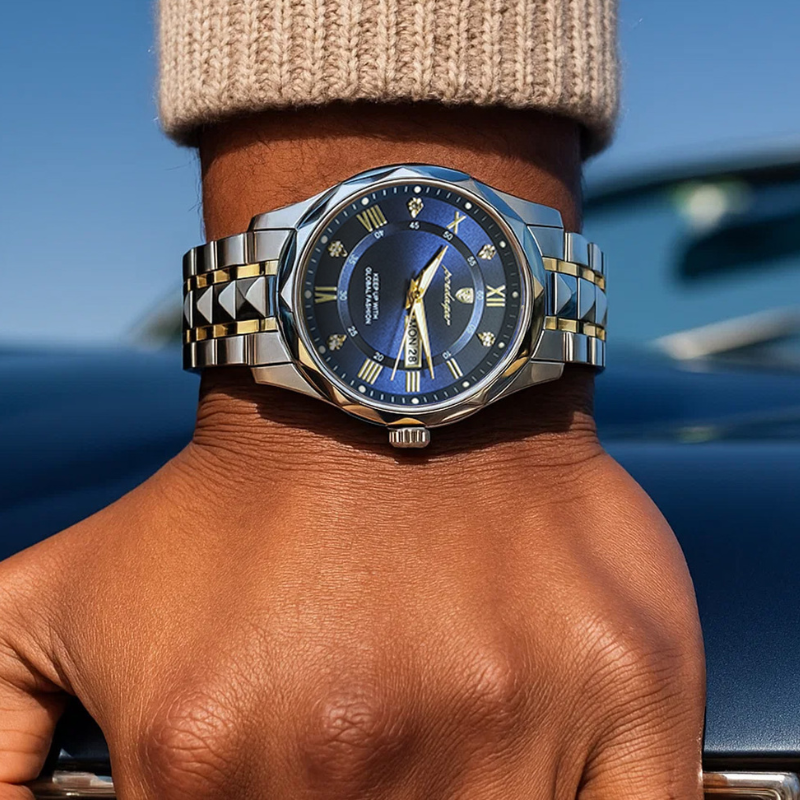 Close-up of Maverick Luxe men's watch in stainless steel gold two-tone with blue dial, date display, and luminous hands, worn on a man's wrist with a beige sweater.