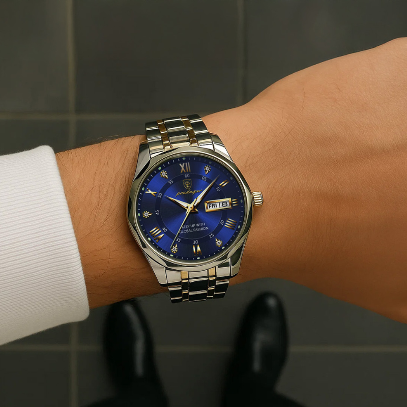 Maverick Luxe men's watch in stainless steel and gold, featuring a blue dial with date display and luminous hands, worn on a man's wrist with a white shirt and black shoes, on a dark tiled floor.