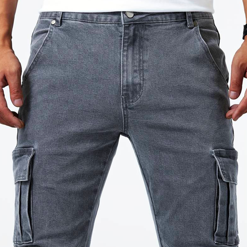 Close-up detail of the front of the gray Metro Blue Cargo Trousers, highlighting the cargo pockets, front pockets, and adjustable waistband button closure. Shows the denim fabric texture.