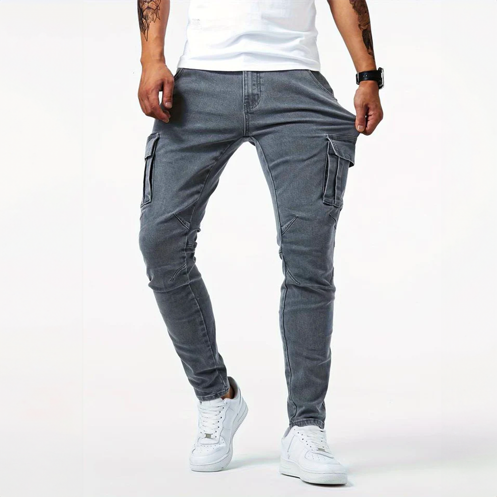 Front view of men's Metro Blue Cargo Trousers in gray, worn by a model demonstrating the adjustable waistband. The trousers feature prominent cargo pockets and a modern urban denim style.