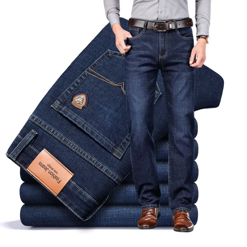 Man wearing dark blue Cityscape Trousers men's premium cotton classic fit pants, standing next to a stack of folded dark blue pants.