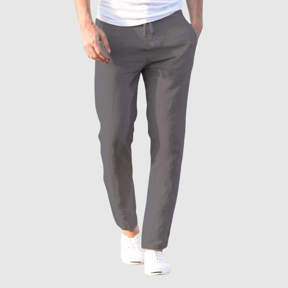 Men's Seaside Retreat relaxed fit linen pants in gray, worn by a model with white sneakers. Ideal for casual wear and summer fashion, offering breathable comfort.