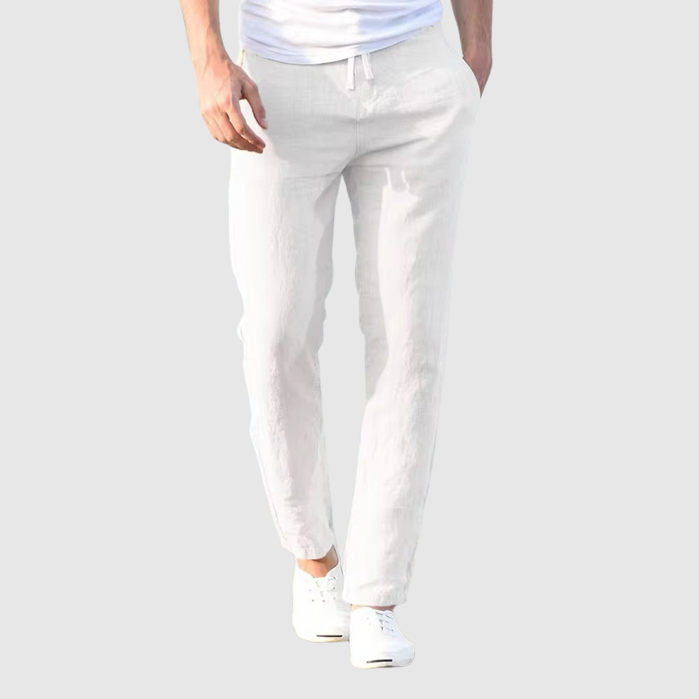 Seaside Retreat men's white linen pants with relaxed fit, shown on a model wearing a white t-shirt and white sneakers. Ideal for casual wear and summer fashion.