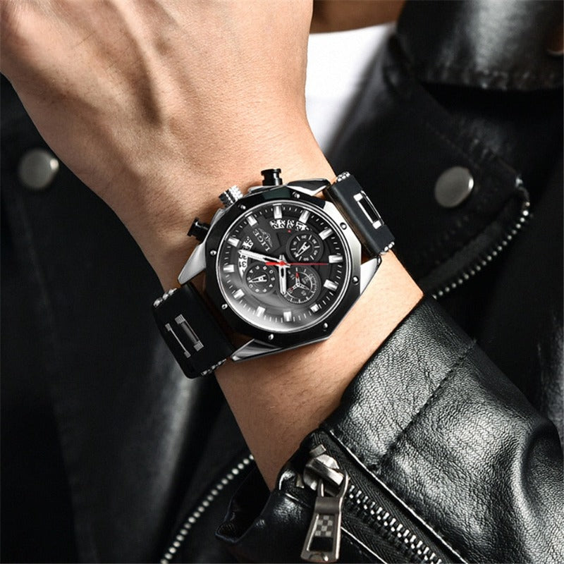 Close-up of a man's wrist wearing the Skyline Aviator men's quartz watch. The watch features a silver case, black dial with luminous hands, chronograph subdials, and a black silicone strap. The man is wearing a black leather jacket.