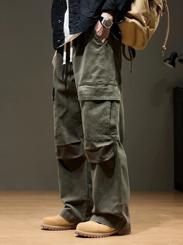 Summit Trail Cargo Pants in green, worn by a man from a side view, showcasing the relaxed fit, large utility pockets, and reinforced stitching. Paired with tan boots and a backpack, ideal for outdoor wear.