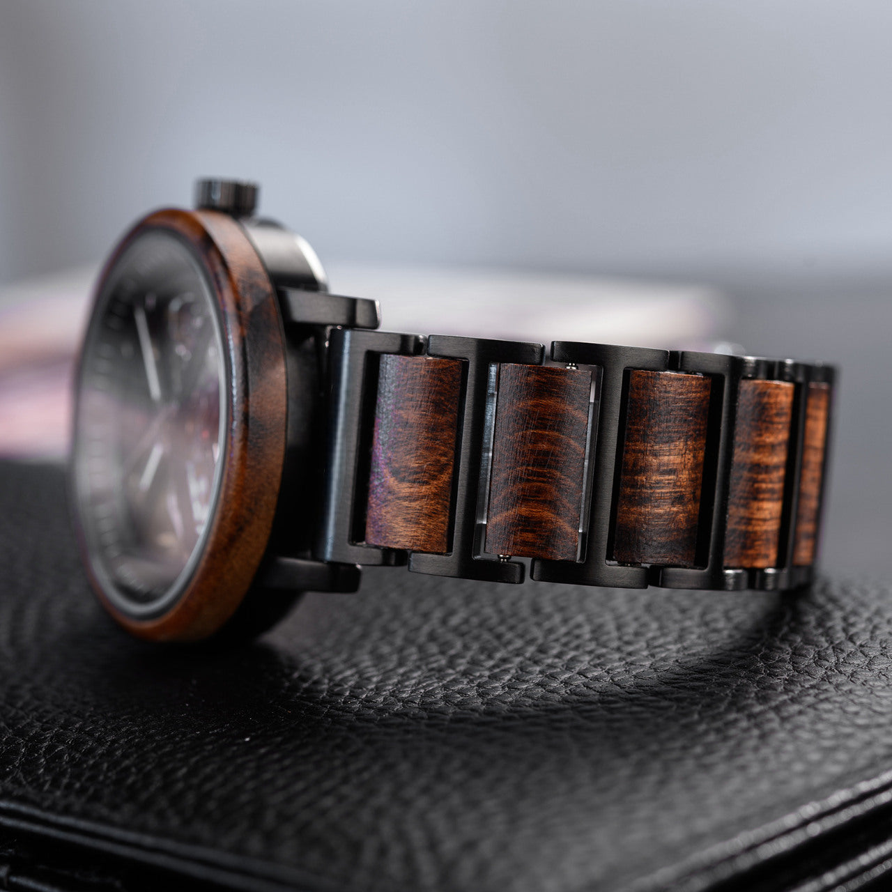 Terra Brown men's wooden watch natural finish, close-up side view showing dark brown wooden links watch face bezel resting on dark textured surface.
