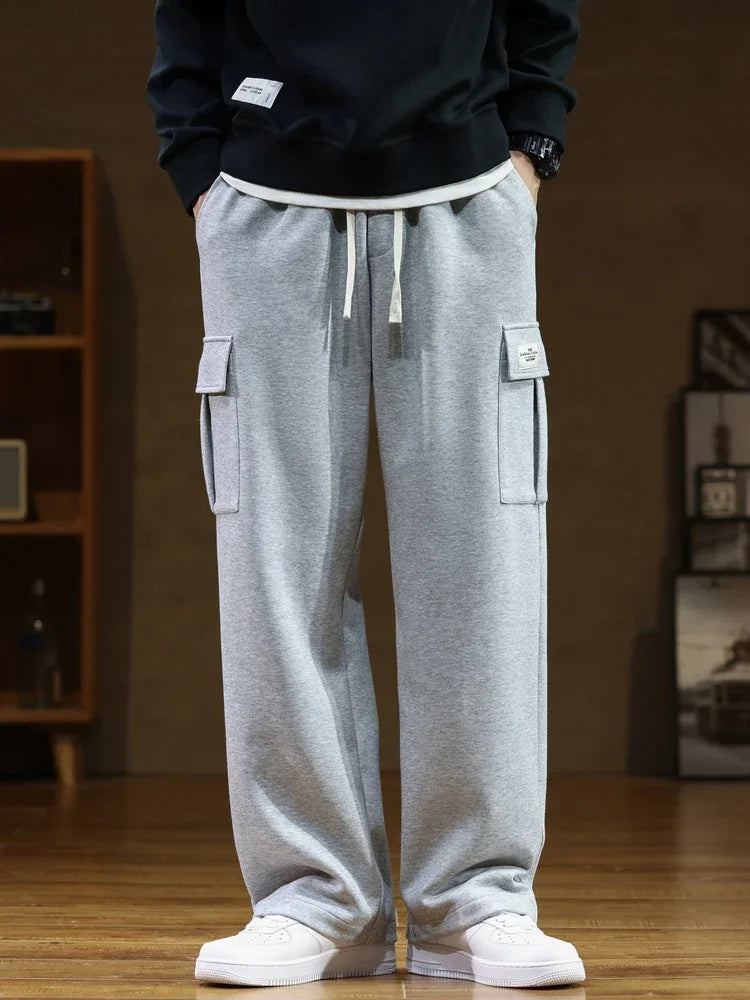 Urban Nomad light gray cargo sweatpants made from soft cotton, featuring a relaxed fit, front utility pockets, and a visible drawstring. Worn by a person from the front, hands in pockets.