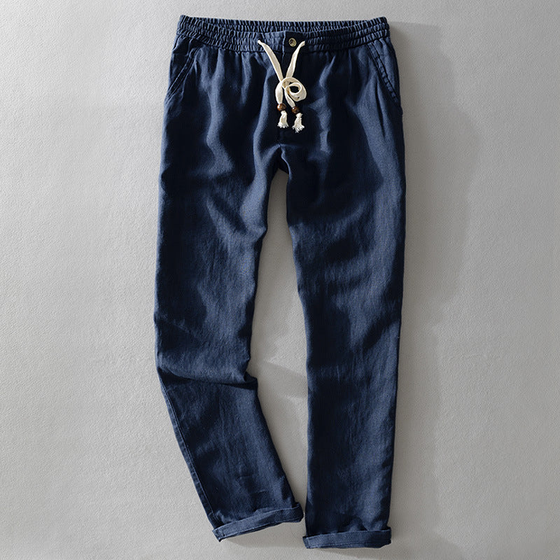 Dark blue Willow Grove casual linen pants with a relaxed fit, displayed in a flat lay, front view. The pants have an elastic waistband with a light-colored drawstring and decorative tassels, and the leg hems are cuffed.