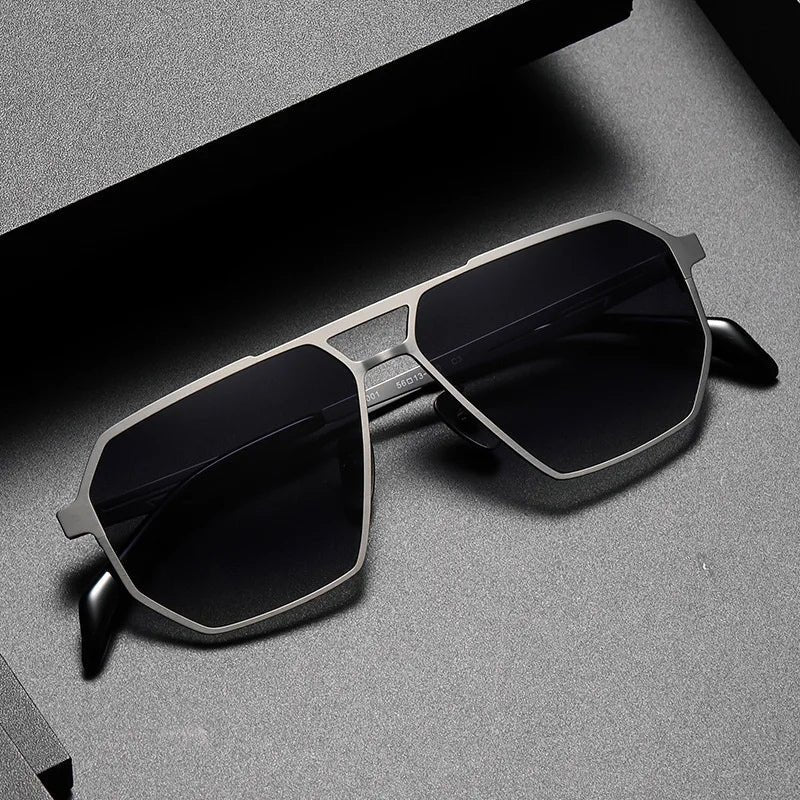 Aero Edge Aviator Sunglasses in titanium with a sleek silver finish and dark octagonal lenses, viewed from a top-down angle on a grey background.