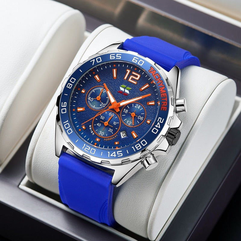 Apex Dusk men's quartz watch with luminous hands and date display, featuring a blue dial, orange accents, and a blue silicone strap, presented on a white display stand.