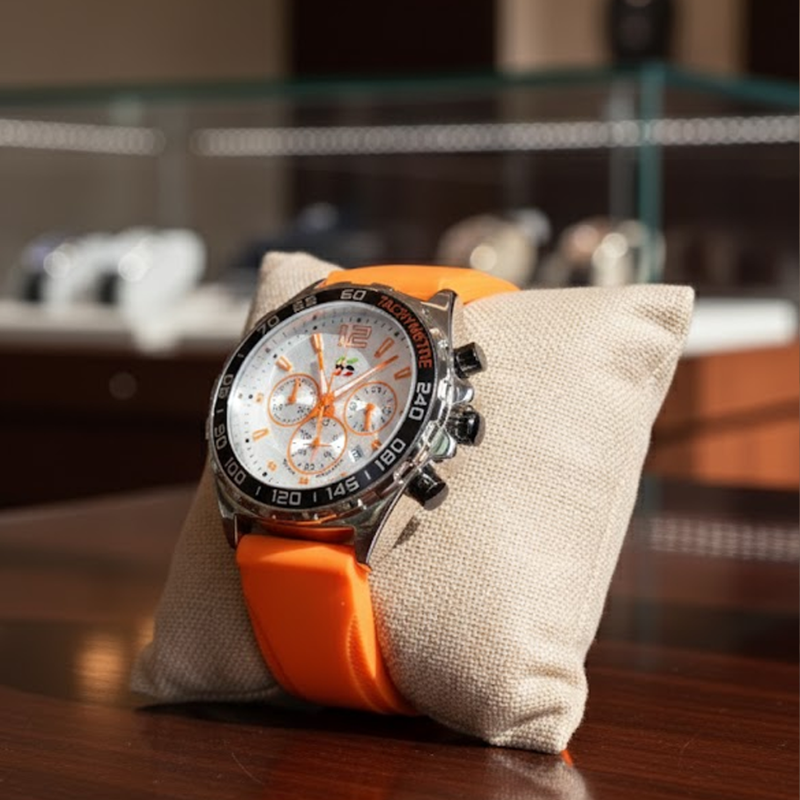 Apex Dusk men's quartz watch with luminous hands and date display, silver case, white dial, and orange silicone strap, presented on a beige display cushion.