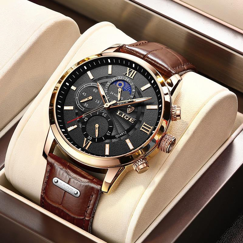 The Aurelius Timepiece, a gold-cased men's watch with a black dial, brown leather strap, luminous hands, and moon phase feature, displayed in a watch box. The watch features multiple subdials and Roman numerals.