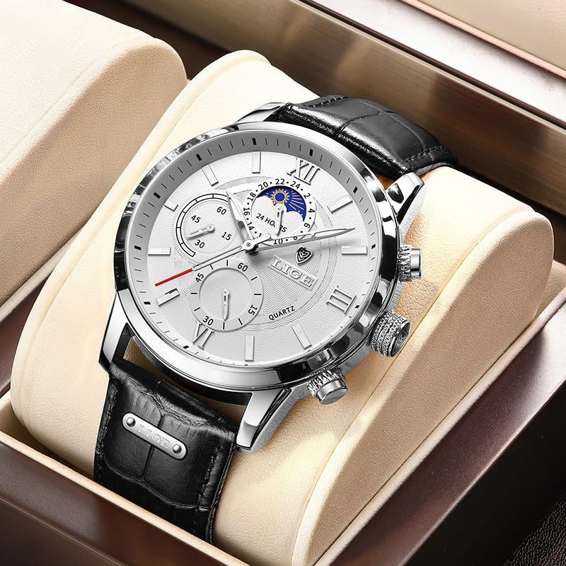 The Aurelius Timepiece, a silver-cased men's watch with a white dial, black leather strap, luminous hands, and moon phase feature, displayed in a watch box. The watch features multiple subdials and Roman numerals.