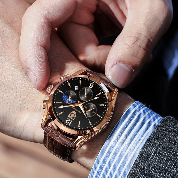 Aventadori men's rose gold watch with a black dial and brown leather strap worn on a man's wrist, showing a striped shirt and grey suit jacket.