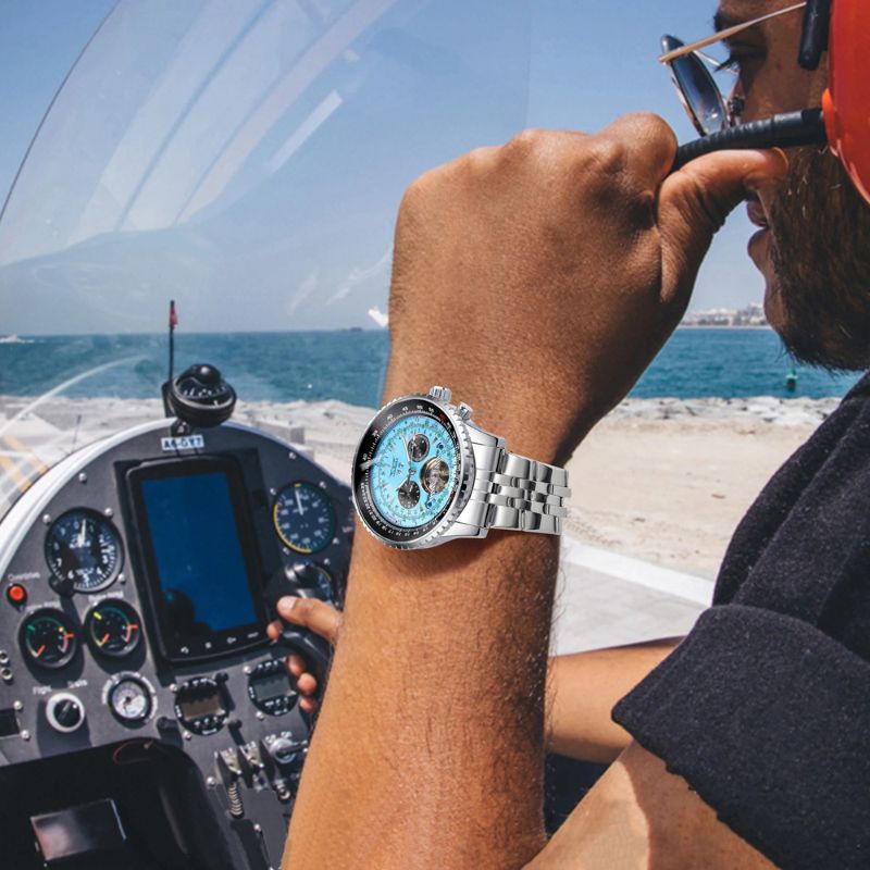 Man wearing the Celestial Elegance automatic men's watch with a silver blue dial on his wrist, seated in an aircraft cockpit with the ocean visible in the background, highlighting its casual style.