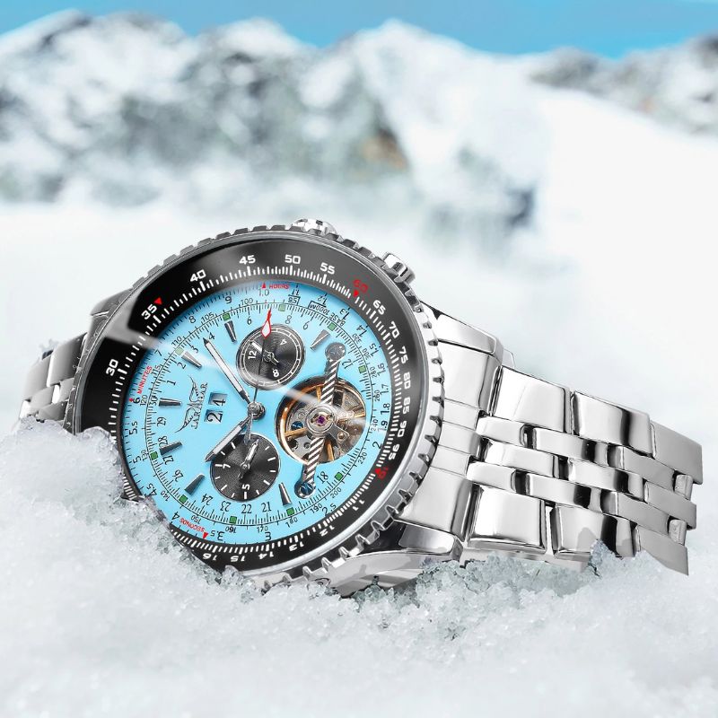 Celestial Elegance automatic men's watch with a silver blue chronograph dial and stainless steel band, elegantly displayed on a snowy surface with majestic mountains in the background.