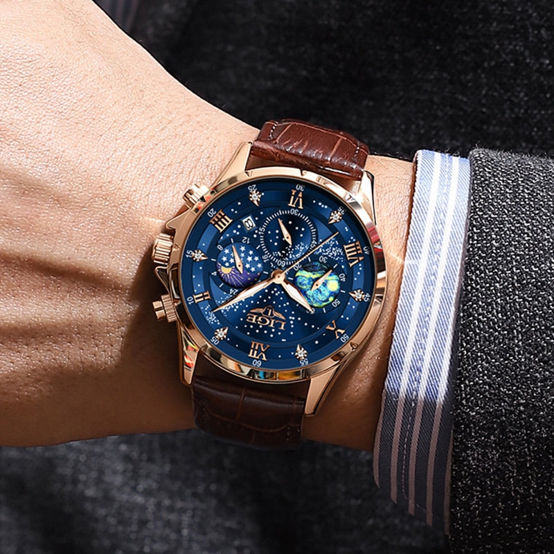 Men's Celestial Timekeeper watch in rose gold with a blue starry chronograph dial and brown leather strap, worn on a man's wrist with a suit jacket.