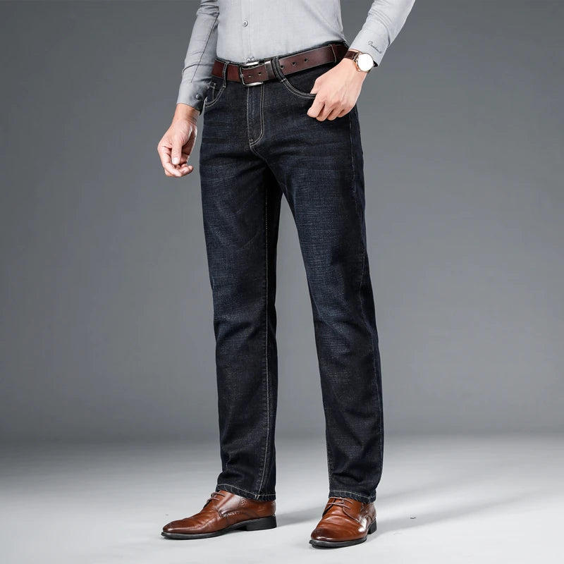 Full shot of a man wearing dark blue men's premium cotton classic fit trousers, paired with a grey shirt, brown belt, and brown dress shoes.