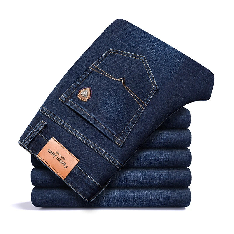Stack of dark blue men's premium cotton classic fit trousers, showcasing the back pocket detail with stitching, a small emblem, and a leather-like patch.