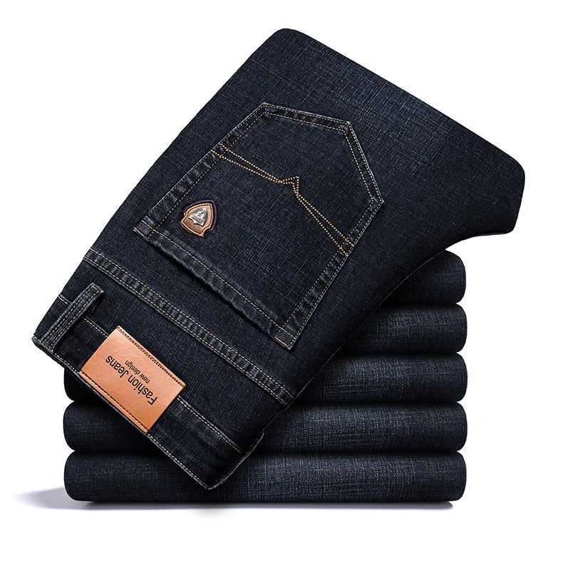 Stack of folded black Cityscape Trousers, showing the back pocket detail and a leather brand patch.