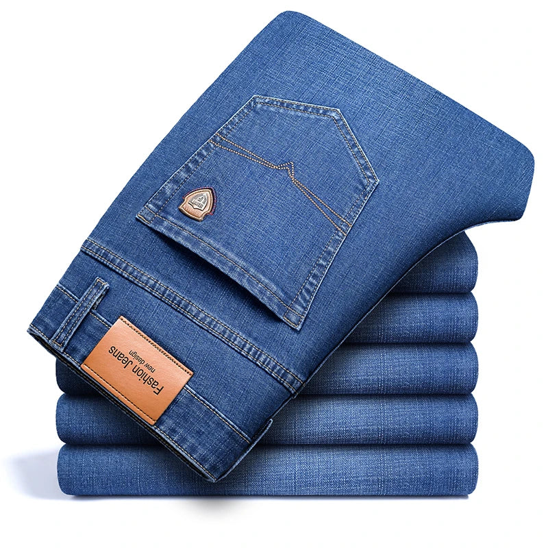 Stack of light blue men's premium cotton classic fit trousers, showcasing the back pocket detail with stitching, a small emblem, and a leather-like patch.