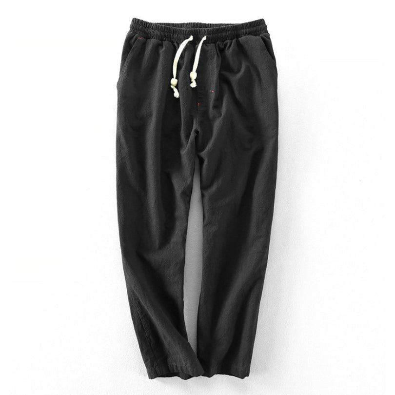 A pair of black Edo Escape Japan-style linen trousers, laid flat on a light gray background, showcasing a relaxed fit, elastic waistband, and a contrasting cream-colored drawstring.