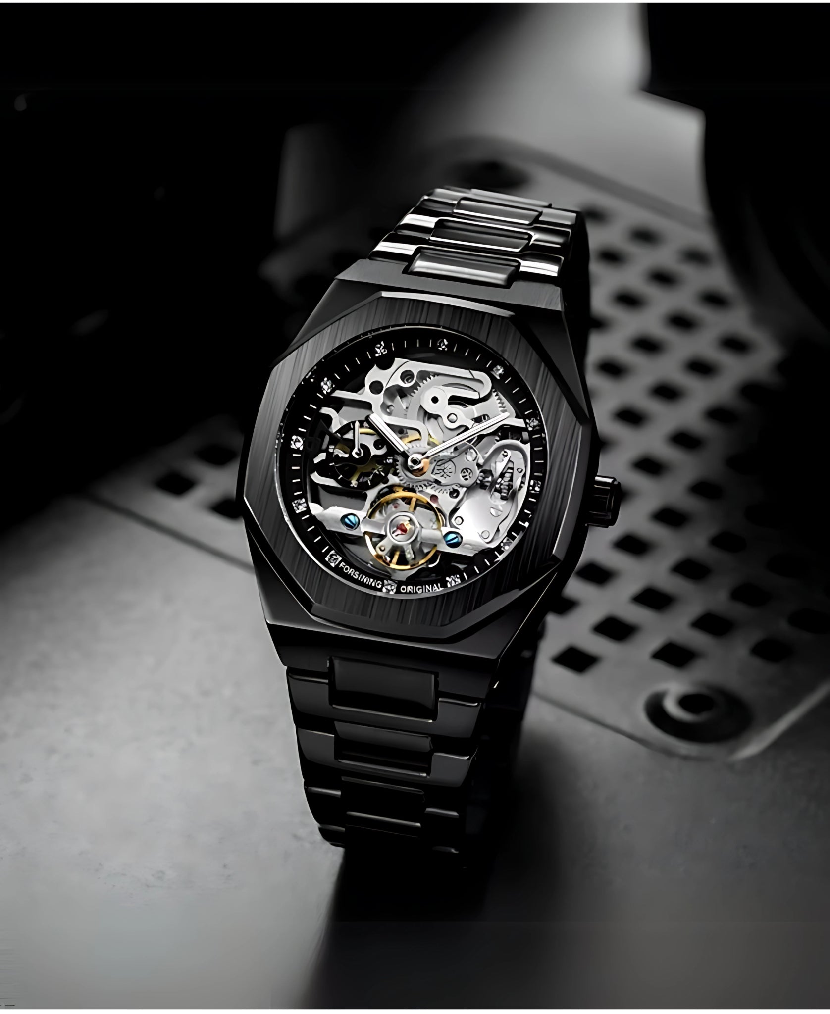 Close-up view of a black mechanical skeleton watch with visible gears and mechanisms, resting on a dark, textured surface. The watch has a black metal strap and case, highlighting its intricate design.
