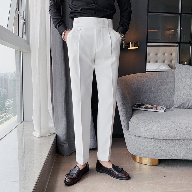 A man wearing white Elysian high-waisted slim-fit trousers in premium fabric, shown in a full-body shot standing by a window, paired with a black shirt and loafers.