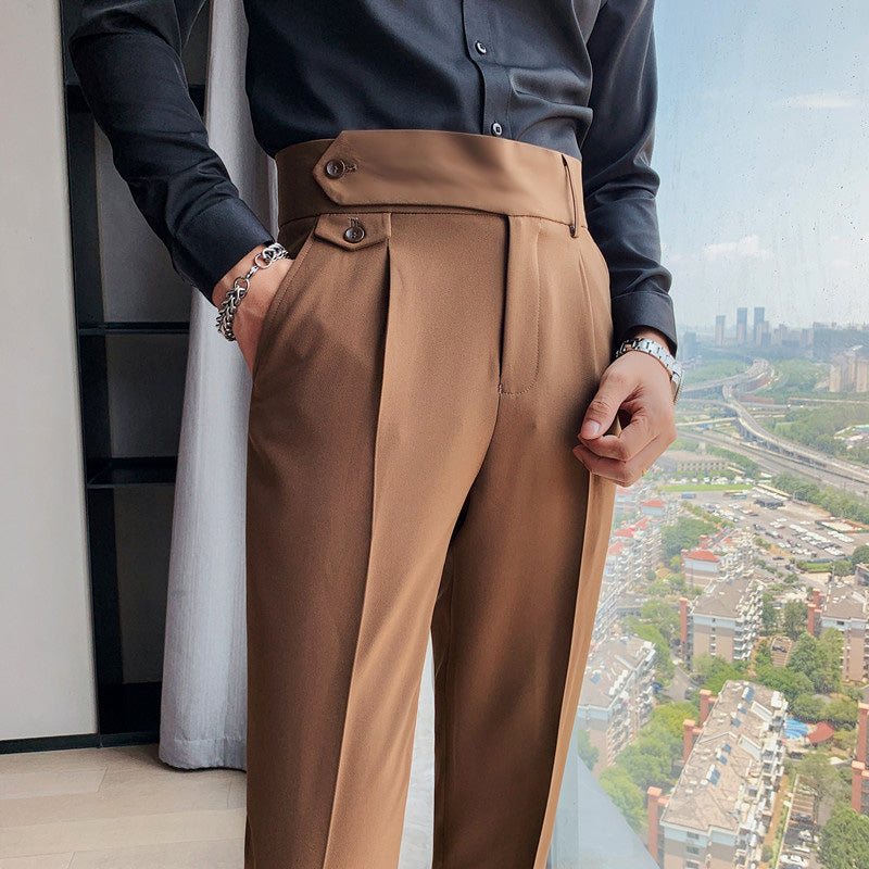 A close-up shot of a man wearing Elysian high-waisted slim-fit trousers in camel. The image highlights the tailored waistband, pleats, and side pockets of the premium fabric trousers, paired with a black shirt.
