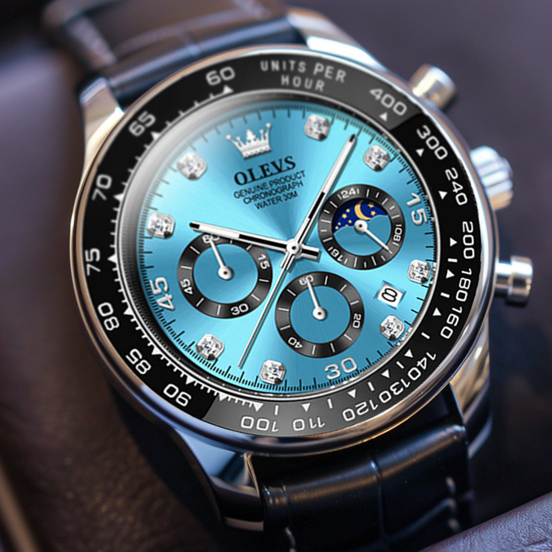 Angled view of a men's Elysium Timepiece watch with a blue dial, silver case, and black leather strap, showcasing the side profile crown. The watch features a chronograph, date display, and luminous hands.