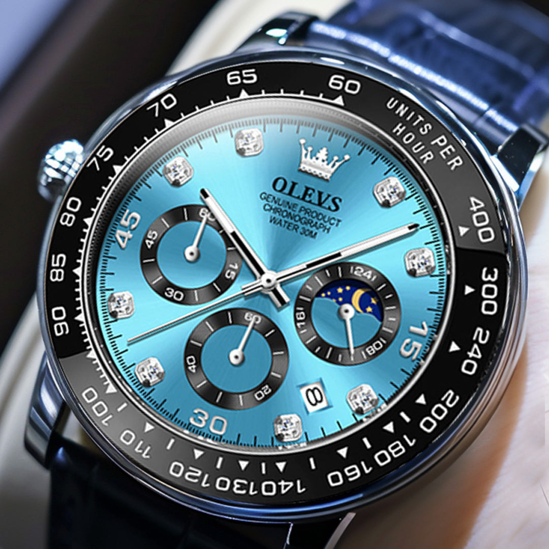 Close up of a men's Elysium Timepiece watch with a blue dial, silver case, and black leather strap. The watch features a chronograph, date display, and luminous hands.
