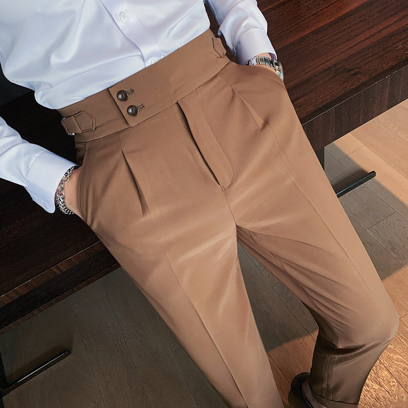 Close-up view of Elysian camel high-waisted slim-fit trousers on a man, highlighting the unique buttoned waist detail and premium fabric texture. The trousers are paired with a white shirt.