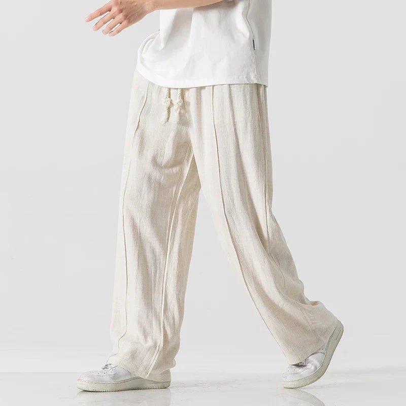 Elysium Drift beige linen sweatpants with a relaxed fit, shown from a side view in a walking pose, paired with a white t-shirt.