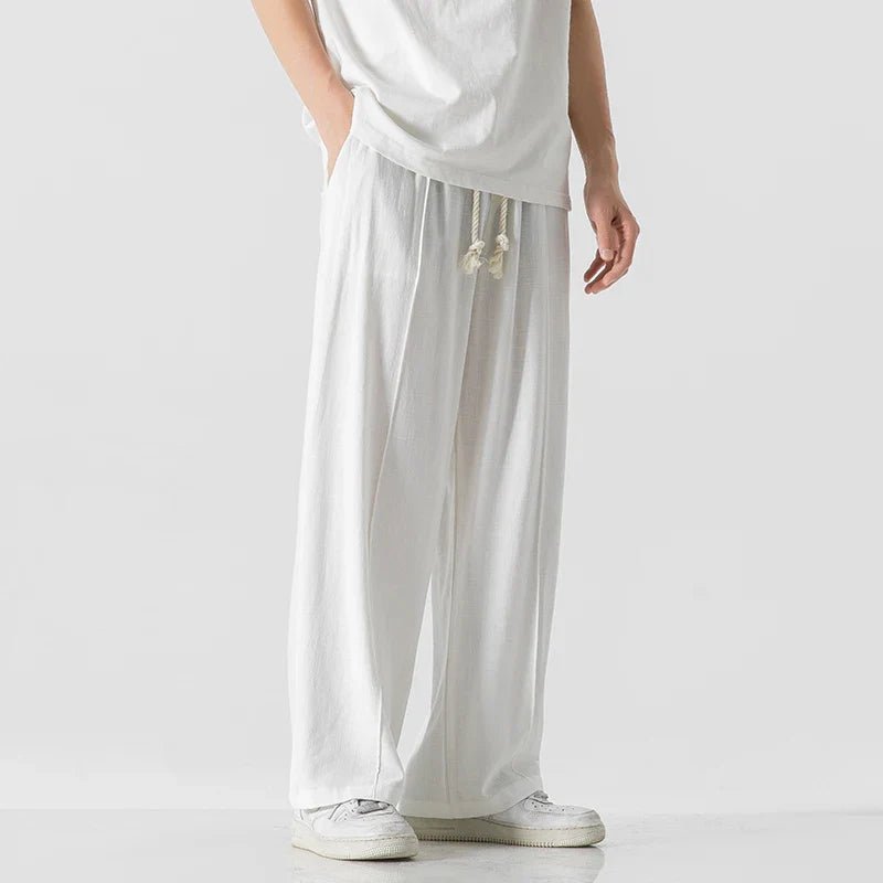 Elysium Drift white linen sweatpants with a relaxed fit, shown from a side view with a visible drawstring, paired with a white t-shirt.