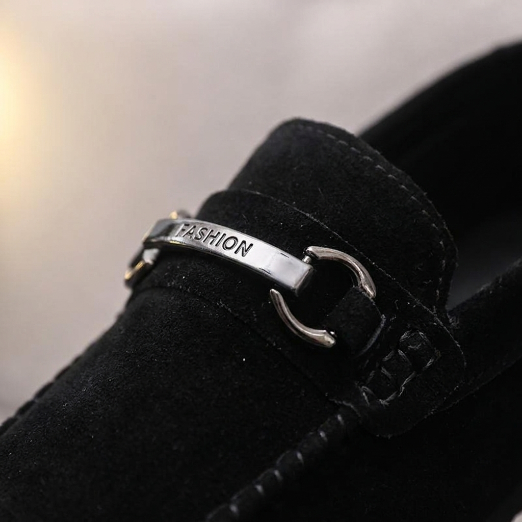 Close-up front detail of black bucket loafer showing unique metal buckle, open toe, and foam rubber sole