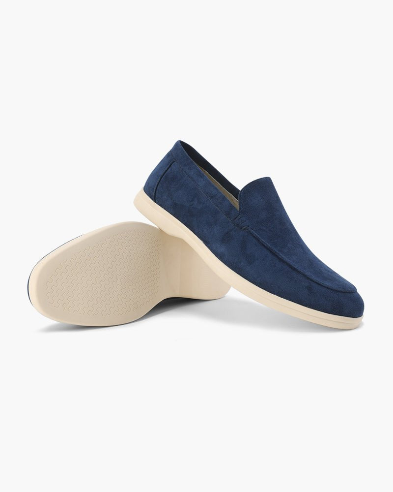 Heritage Luxe Suede Loafers with Classic Stitching in Marine Blue, shown from a side view with one loafer upright and the other on its side revealing the textured cream sole.