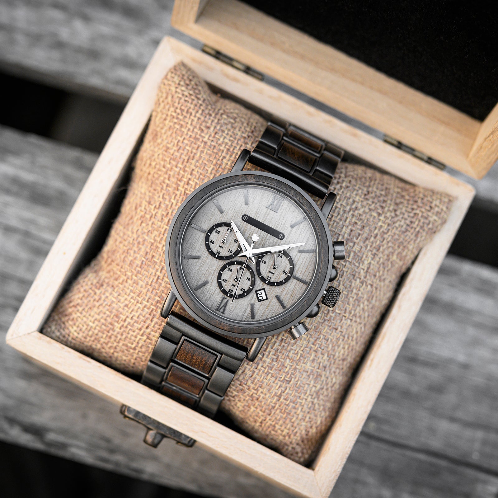 Heritage Oak men's watch with natural wood and dark metal band, presented inside an open light wood gift box on a burlap cushion.