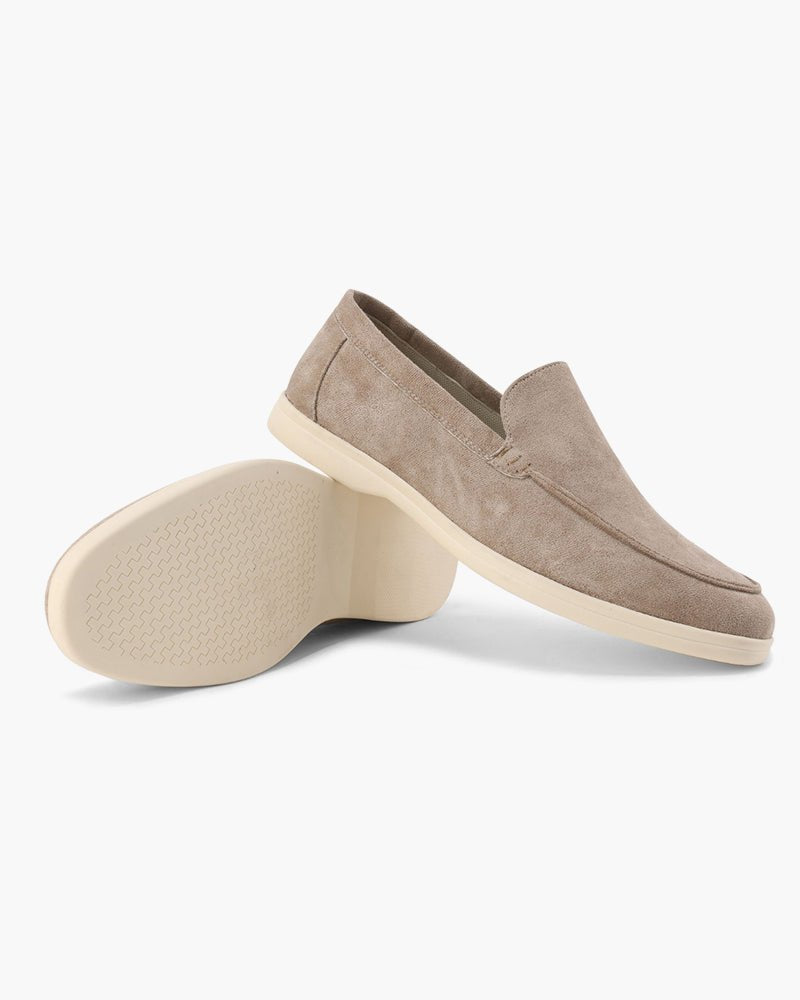 Pair of Heritage Luxe Mocha suede loafers with classic stitching, one upright showing the top and side, the other on its side revealing the textured sole. White background.