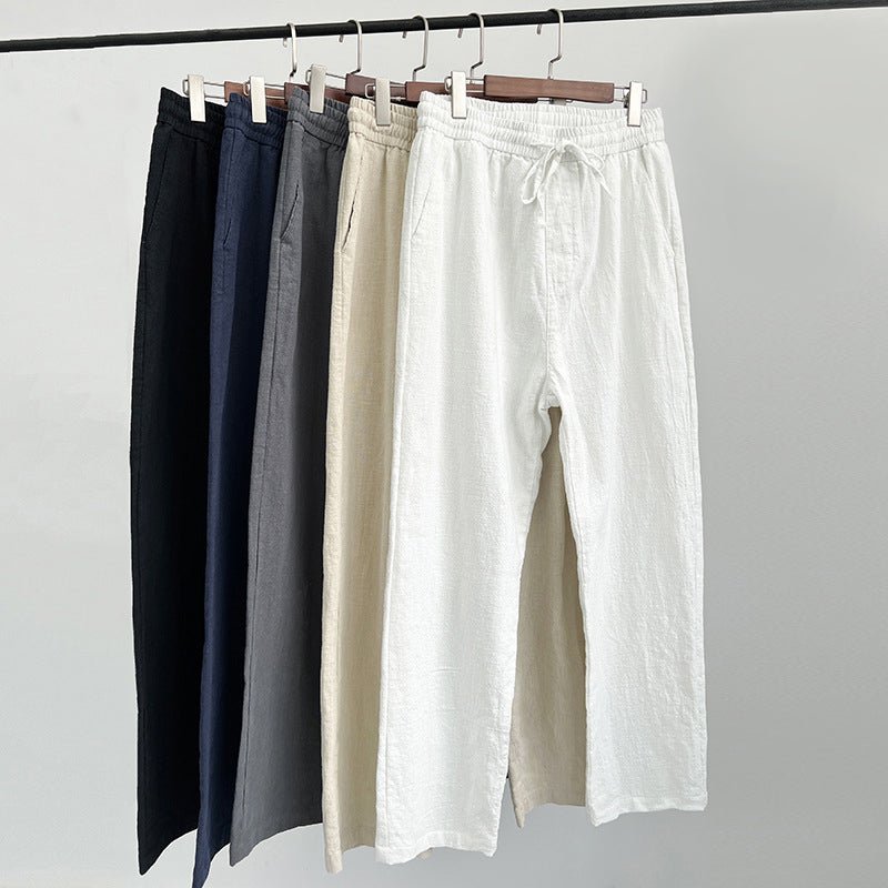 Five pairs of Luxe Retreat Comfy Linen Pants with Relaxed Fit hanging on a rack, showcasing available colors: black, navy blue, gray, khaki, and white.