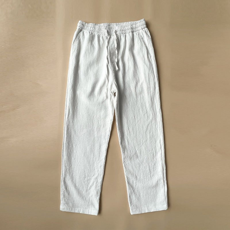 A single pair of white Luxe Retreat Comfy Linen Pants with Relaxed Fit, featuring an elastic drawstring waist and side pockets, laid flat on a neutral brown background.