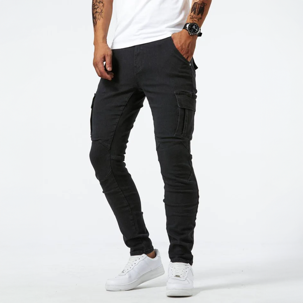 Metro Blue Cargo Trousers. Side view of a male model wearing black denim cargo pants, highlighting the slim fit and side pocket.