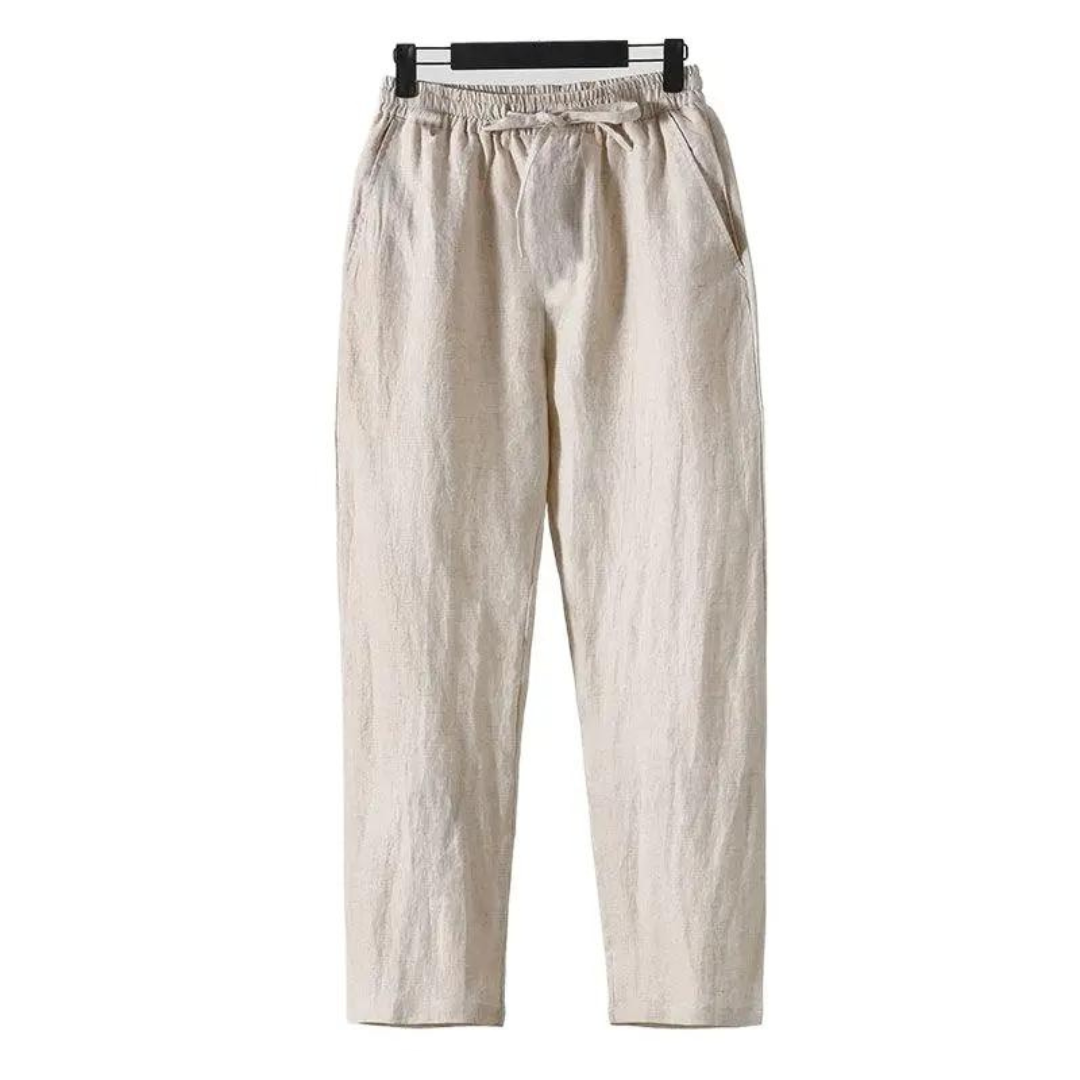 Sahara Whisper beige linen pants, straight fit, soft touch finish, hanging on a hanger, front view. Lightweight, breathable, comfortable trousers.
