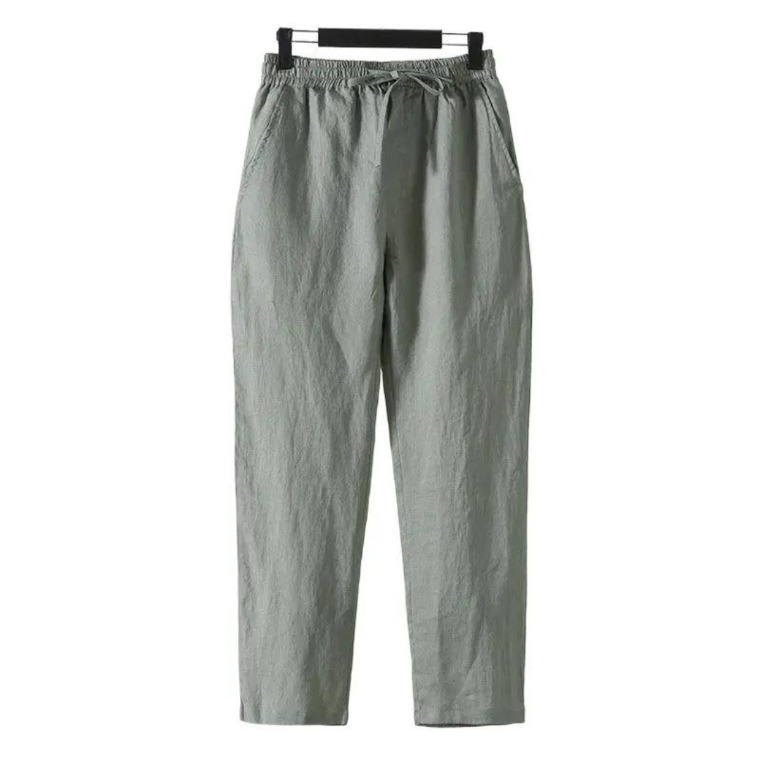 Sahara Whisper green linen pants, straight fit, soft touch finish, hanging on a hanger, front view. Lightweight, breathable, comfortable trousers.