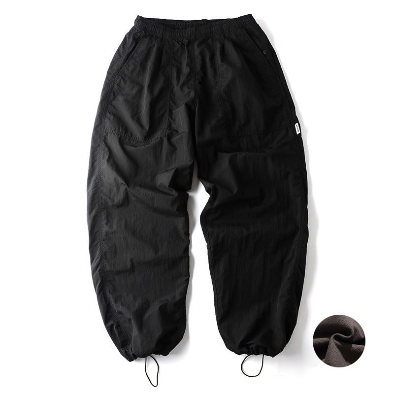 Front view of Sakura Breeze men's waterproof breathable casual pants in black, featuring a relaxed fit, adjustable drawstring cuffs, and a small circular swatch showing the fleece lining texture.